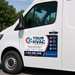 White van with HVAC services branding and contact information on a clear day.