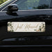 Car with a 'Just Married' decorative car banner featuring flowers and rings on a black car.