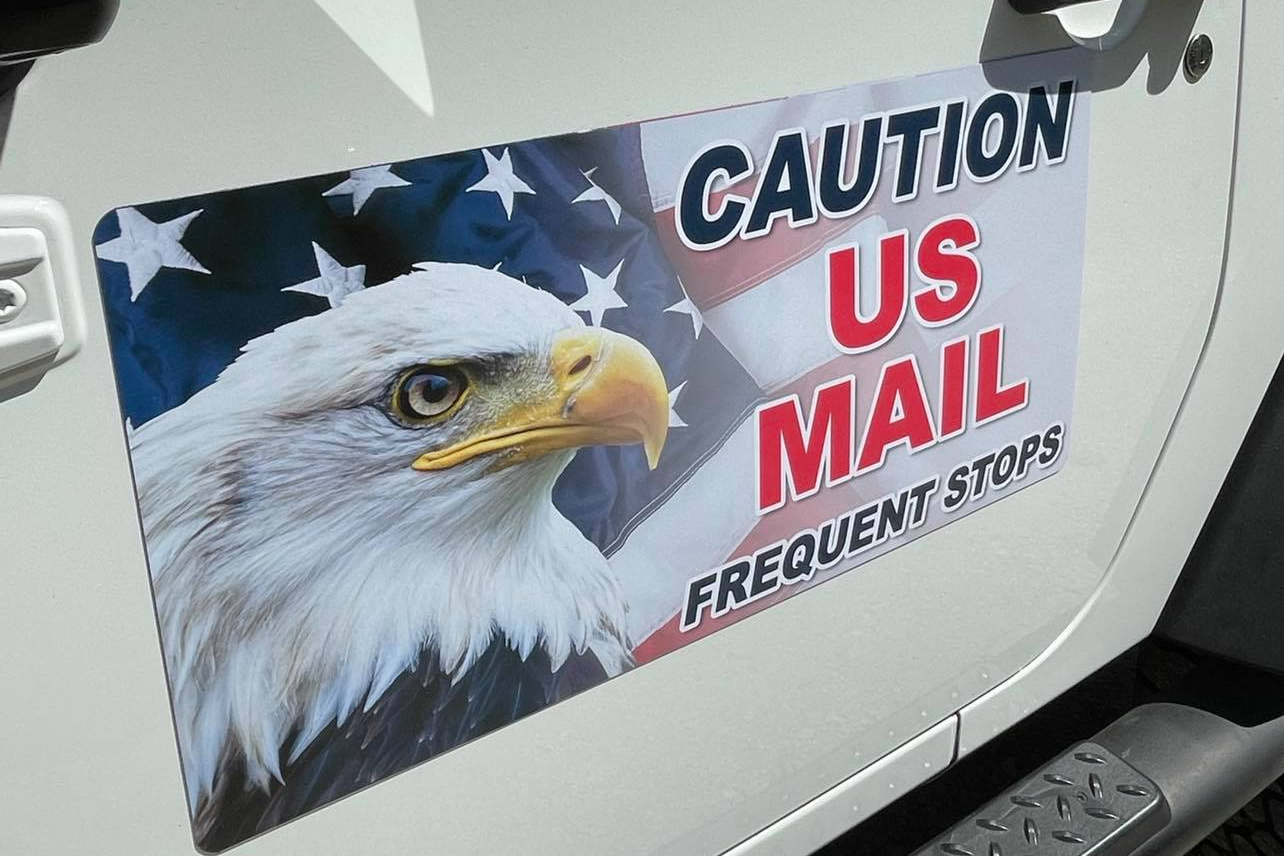 USPS rural carrier magnetic sign installed on a mail delivery vehicle